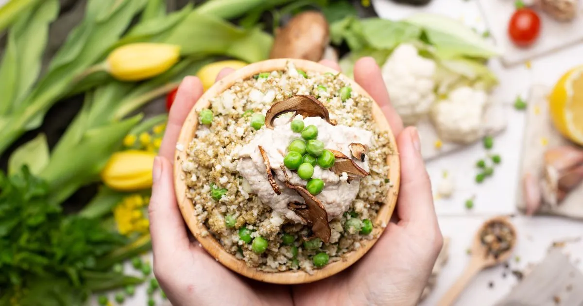 A person displaying a bowl of gluten free dinner, brimming with an array of healthy vegetables.