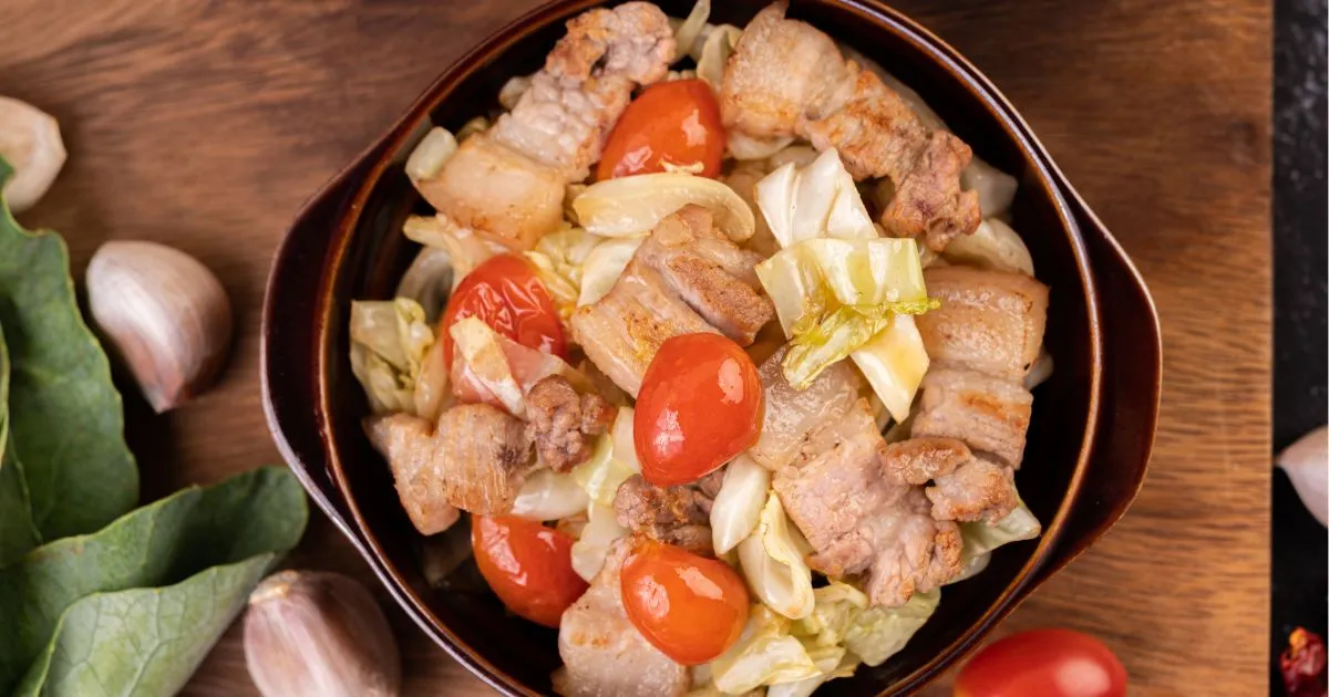 Canned chicken with sautéed vegetables and garlic, presented on a wooden table surface.